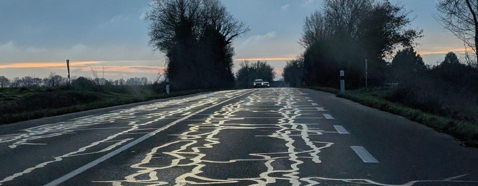 Une route avec des "serpentins" de bitume qui dessinent de l'art routier